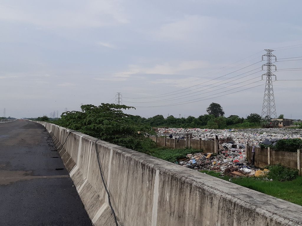 Kondisi tumpukan sampah yang diapit proyek Tol Cibitung Cilincing dan Kali Cikarang Bekasi Laut, di Desa Sumberjaya, Tambun Selatan, Kabupaten Bekasi, pada Selasa (25/1/2022) sore.