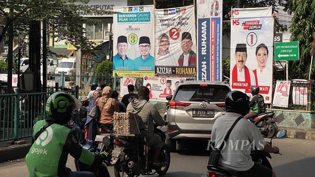Warga melintasi Baliho para calon kepala daerah Pilkada Kota Tangerang Selatan, Banten, pada Pilkada Serentak 2020 di bawah jalan layang Ciputat, Tangerang Selatan, Sabtu (14/11/2020).  