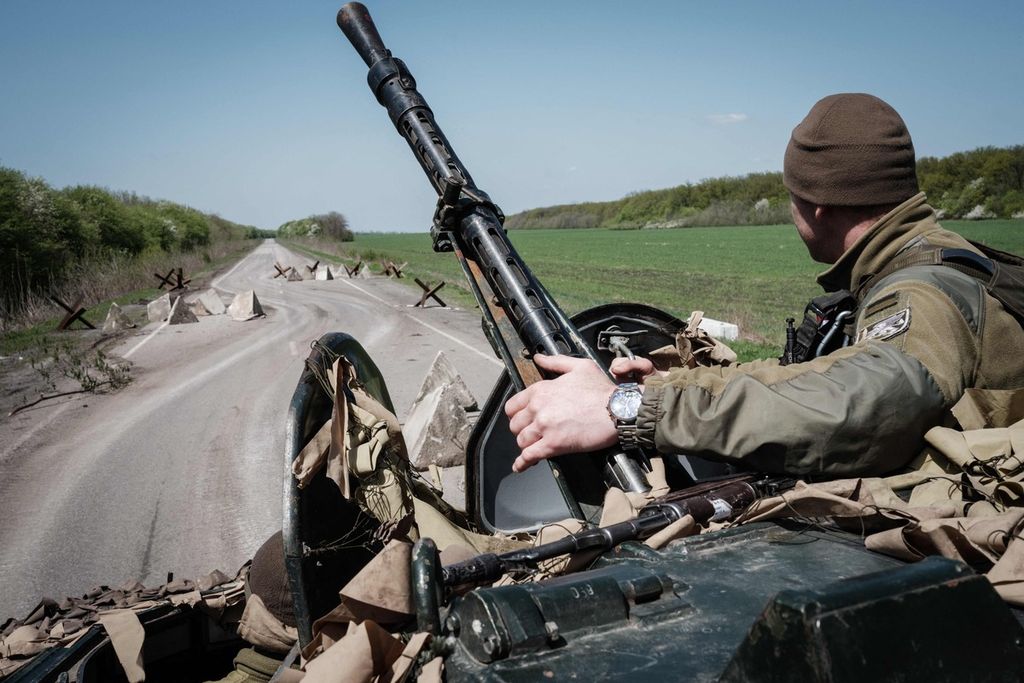 Seorang tentara Ukraina duduk di atas kendaraan angkut lapis baja (APC) yang melaju di sebuah ruas jalan dekat Slovyansk, Ukraina timur, Selasa (26/4/2022), saat invasi Rusia berlangsung di wilayah itu. 