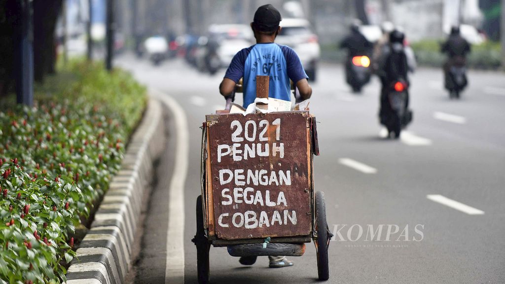 Seorang pemulung menuliskan pengalaman hidupnya selama tahun 2021 di gerobaknya di kawasan Senayan, Jakarta, Jumat (9/7/2021).