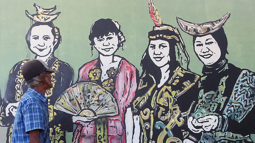 Warga melintasi sambil mengamati gambar mural yang berada di kawasan Pasar Minggu, Jakarta Selatan, Sabtu (31/3/2018). Mural tersebut menampilkan sejumlah model dengan berpakaian adat istiadat daerah di Indonesia. Mural ini dibuat untuk menggambarkan adanya rasa ke-Bhinnekaan Tunggal Ika yang ada di masyarakat Indonesia.