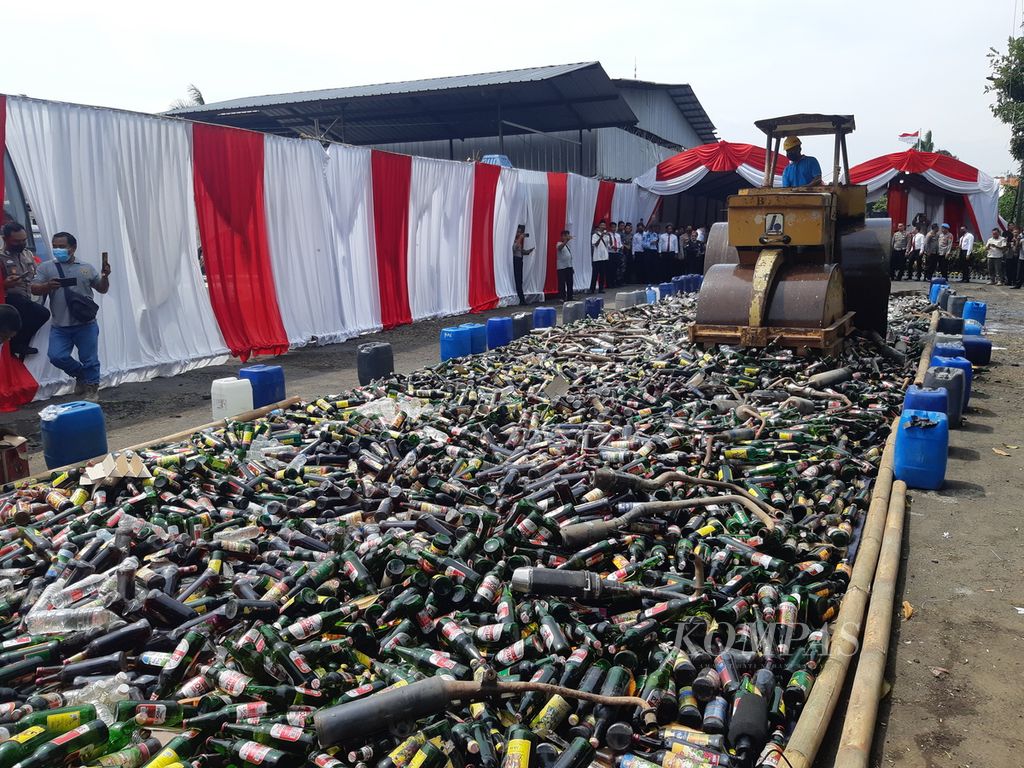 Alat berat menghancurkan tumpukan minuman keras dan knalpot bising di halaman Kepolisian Resor Indramayu, Kabupaten Indramayu, Jawa Barat, Rabu (28/12/2022). Polres Indramayu memusnahkan 19.500 botol miras, 3.750 tuak, 2.870 ciu, dan 103 knalpot bising hasil operasi selama 2022.