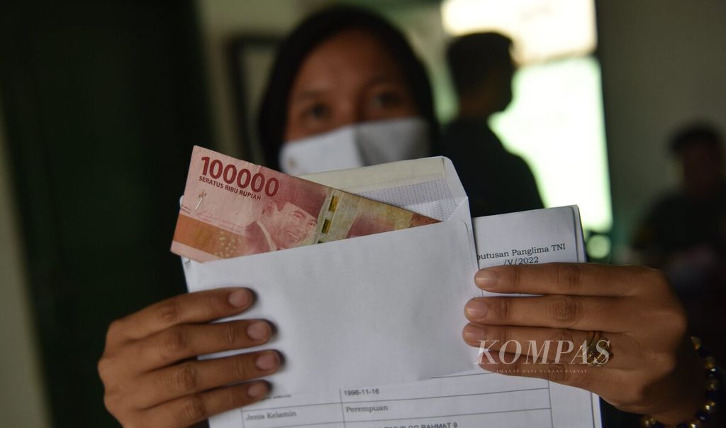 Warga menunjukkan uang yang didapat saat pembagian bantuan langsung tunai (BLT) minyak goreng di halaman Markas Koramil 0830/01 Krembangan, Kota Surabaya, Jawa Timur, Kamis (19/5/2022). 