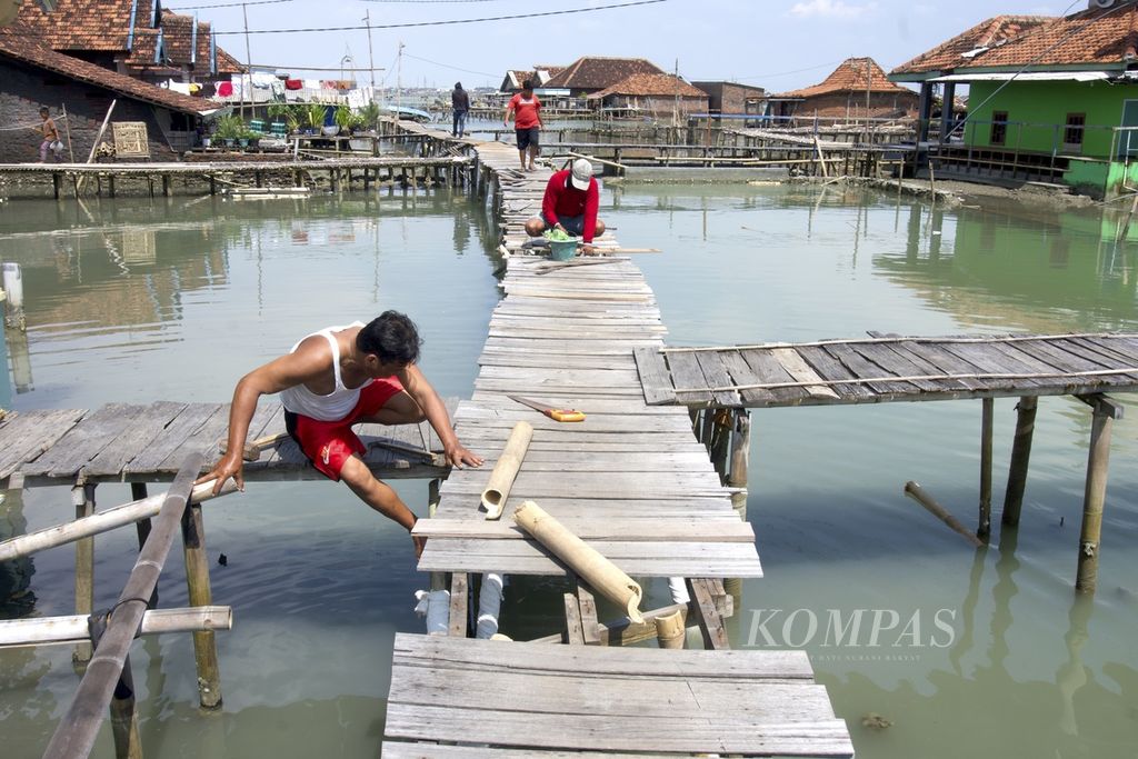 Warga memperbaiki jalanan yang terbuat dari kayu dan bambu di lingkungannya, Dukuh Timbulsloko, Desa Timbulsloko, Kecamatan Sayung, Demak, Jawa Tengah, Selasa (21/3/2023). 