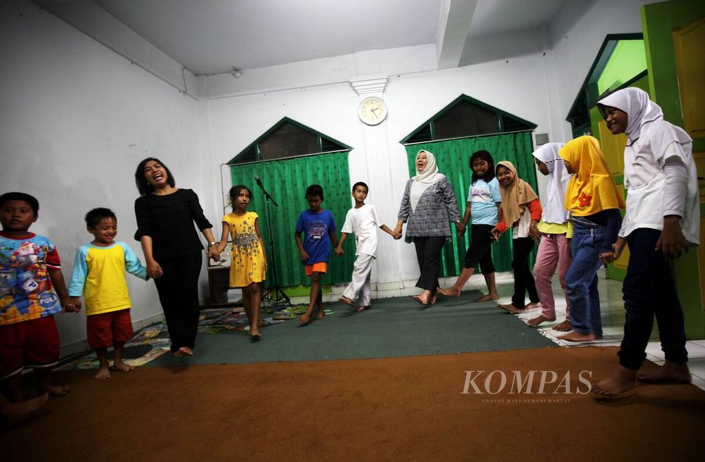 Pendeta Caroline Tuasuun (ketiga kiri) bersama Ketua RT 01 Neng Herti dalam rangkaian kegiatan Sabtu Ceria di Aula Mushola Al Mukhlasiin di RT 01 Kampung Tengah, Kramat Jati, jakarta Timur, setelah didengarkan dongeng pluralisme kepada anak, pertengahan Desember 2017. 