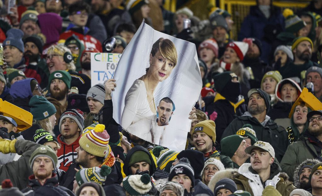 Seorang penggemar memegang poster Taylor Swift dan Travis Kelce selama pertandingan sepak bola<i></i>NFL antara Kansas City Chiefs dan Green Bay Packers pada 3 Desember 2023 di Green Bay, AS. 