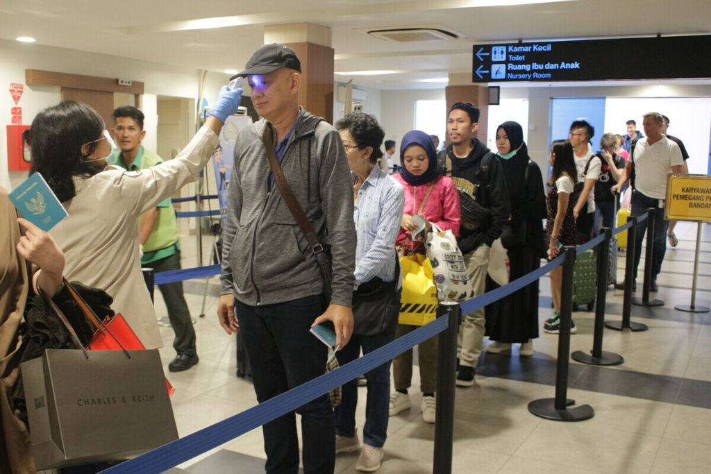 Petugas  bagian epidemiologi Kantor Kesehatan Pelabuhan (KKP) Bandung (kiri) sedang memindai suhu tubuh penumpang dari penerbangan Singapura dengan menggunakan termometer infra merah nonkontak di Bandar Udara Internasional Husein Sastranegara, Kota Bandung, Jawa Barat, Kamis (16/5/2019).