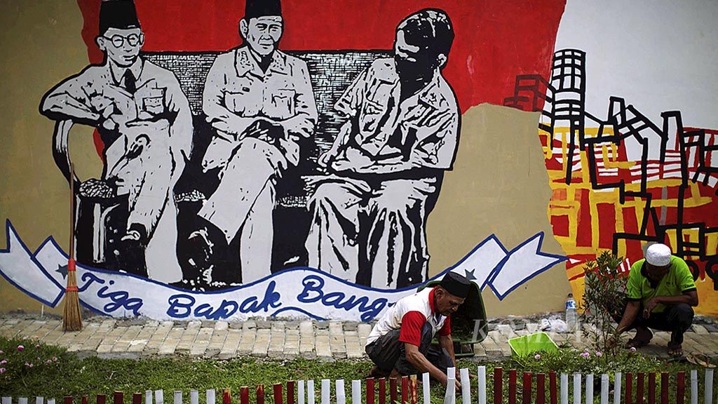 Pekerja merapikan taman di depan mural bergambar Tiga Bapak Bangsa di Lapangan Mega, Kebagusan, Jakarta Selatan, Jumat (7/4). Mural bertema kepahlawanan ini dibuat dengan maksud guna mengingatkan para  generasi muda untuk mengenang jasa para pahlawan.