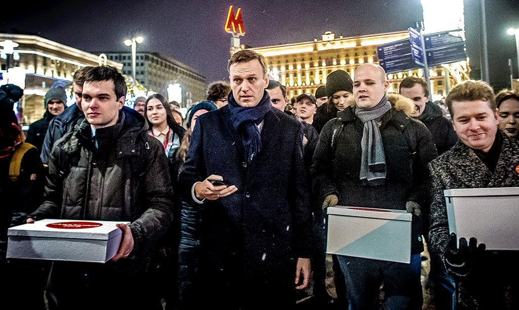 Para pendukung  pemimpin oposisi Rusia, Alexei Navalny (tengah), membawa kotak berisi tanda tangan dukungan terhadap pencalonan Navalny sebagai kandidat oposisi untuk pemilu presiden pada Maret mendatang di Moskwa, Rusia, Minggu (24/12). 