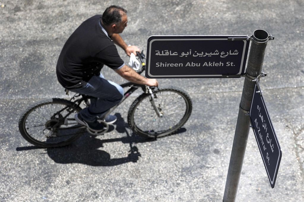  Seorang pesepeda mengayuh sepedanya melewati papan penanda jalan jurnalis Al Jazeera, Shireen Abu Akleh, di kota Ramallah, wilayah pendudukan Tepi Barat, 23 Juni 2022. 