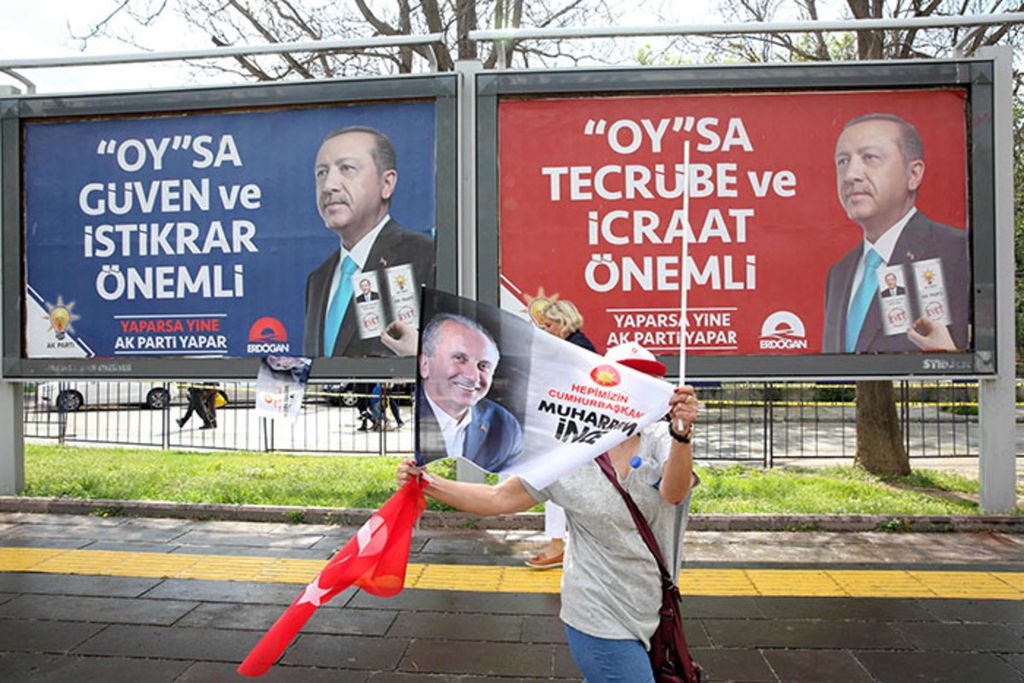 Foto arsip pada 22 Juni 2018 menunjukkan pendukung kandidat presiden dari kubu oposisi di Turki melambaikan bendera saat berjalan melewati poster kampanye bagi Presiden Turki Recep Tayyip Erdogan dalam kampanye di Ankara. 