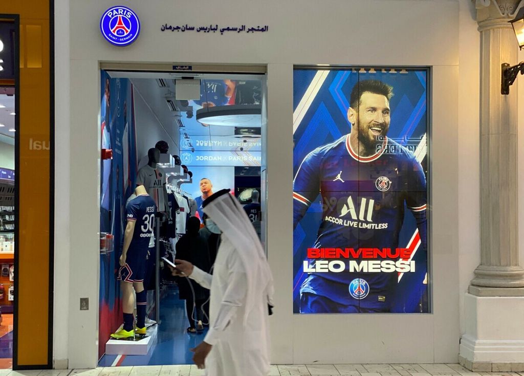 Seorang pria di Qatar berjalan melewati toko yang menjual cendera mata klub Paris Saint-Germain di Doha, Qatar, setelah Lionel Messi menandatangani kontrak dengan PSG tanggal 11 Agustus 2021. 