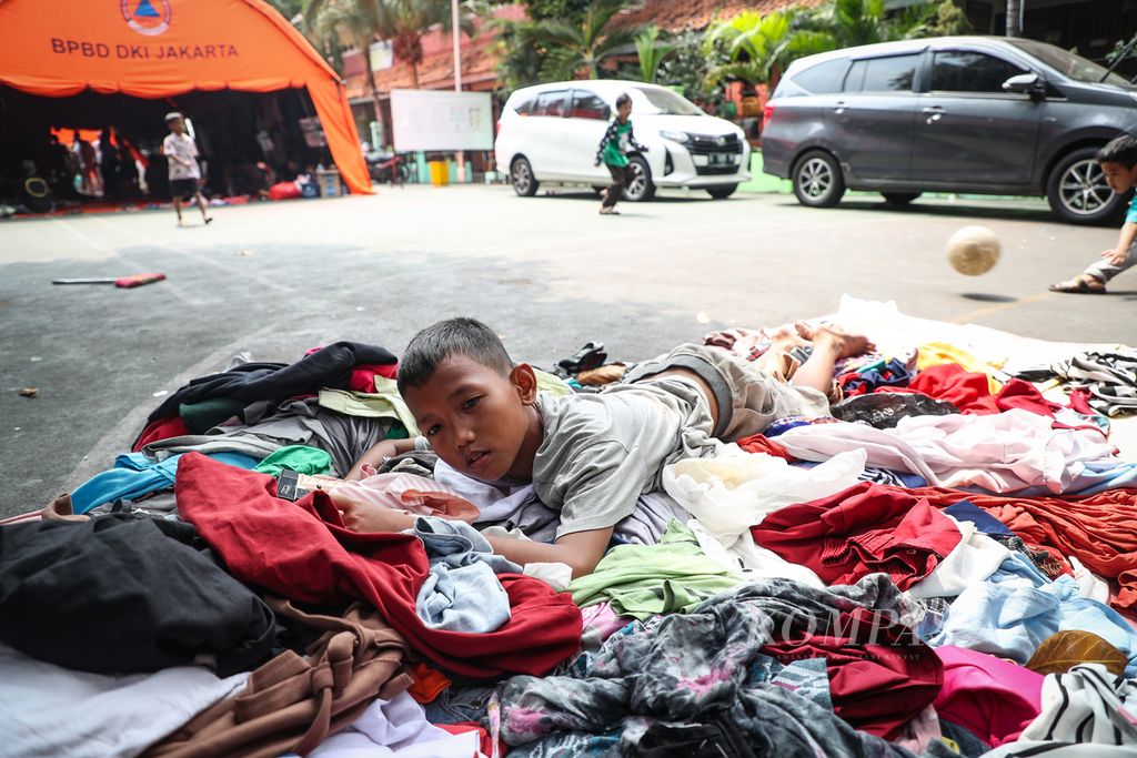 ILUSTRASI. Seorang anak berbaring di atas tumpukan baju di kompleks SDN Duri Utara 01-06, Tambora, Jakarta Barat, Kamis (13/7/2023).  