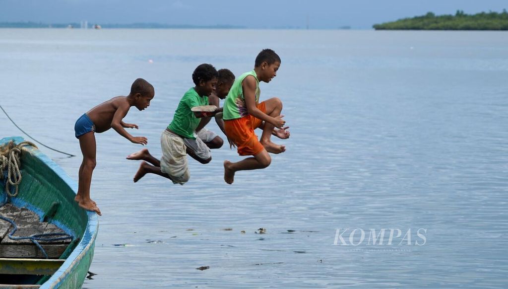 Anak-anak bermain di pantai di kawasan kampung nelayan di Pulau Doom, Kota Sorong, Papua Barat Daya, Minggu (11/6/2023).