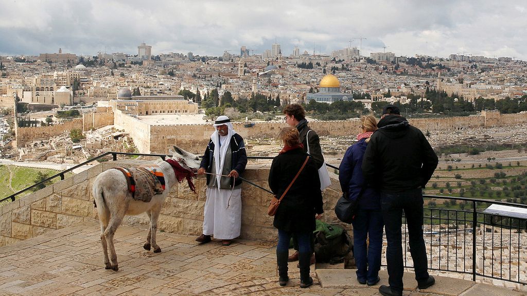 Sejumlah wisatawan  berdiri di dekat pria Palestina yang menawarkan turis untuk menunggangi keledai, Rabu (15/2), di Jerusalem. Pada latar belakang, tampak  bangunan Dome of the Rock.