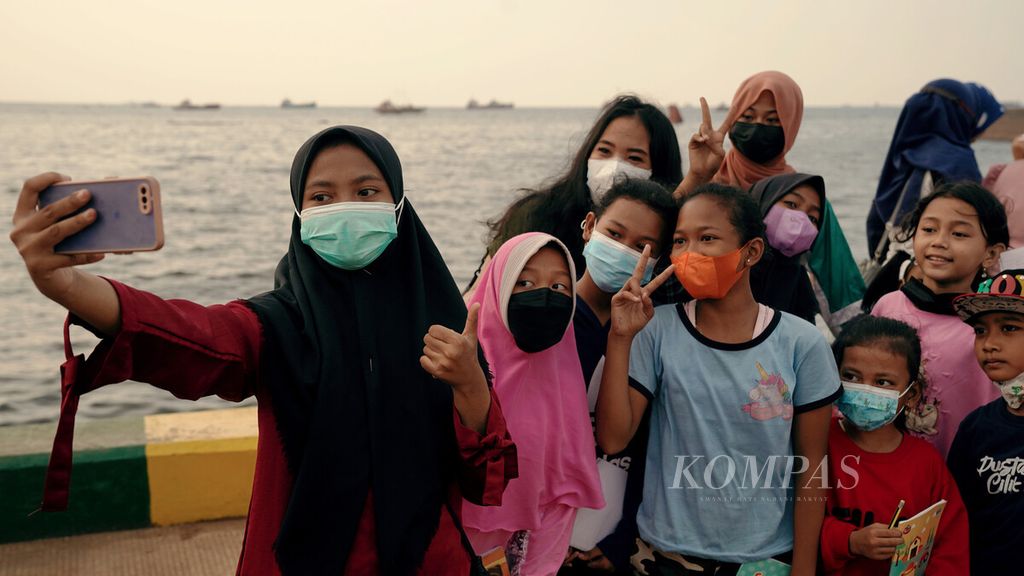 Anak-anak berswafoto saat mengikuti Kelas Jurnalis Cilik yang diadakan di ruang terbuka di pesisir Kalibaru, Cilincing, Jakarta Utara, Agustus 2021. 