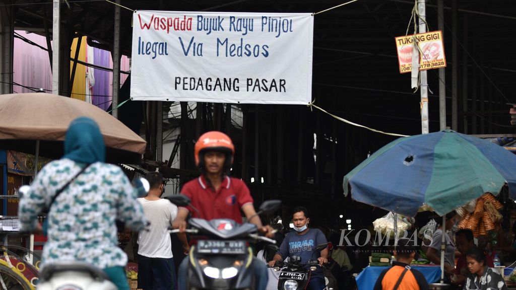 Spanduk ajakan untuk mewaspadai praktik pinjaman online (pinjol) ilegal menghiasi pintu masuk Pasar Muara Angke, Penjaringan, Jakarta Utara, Minggu (14/11/2021). Saat ini setidaknya telah ada lebih dari 19.700 pengaduan pinjol ilegal ke Otoritas Jasa Keuangan (OJK). Bukan hanya soal bunga tinggi yang tidak disadari oleh nasabah, praktik penagihan utang di pinjol juga seringkali menerapkan intimidasi.