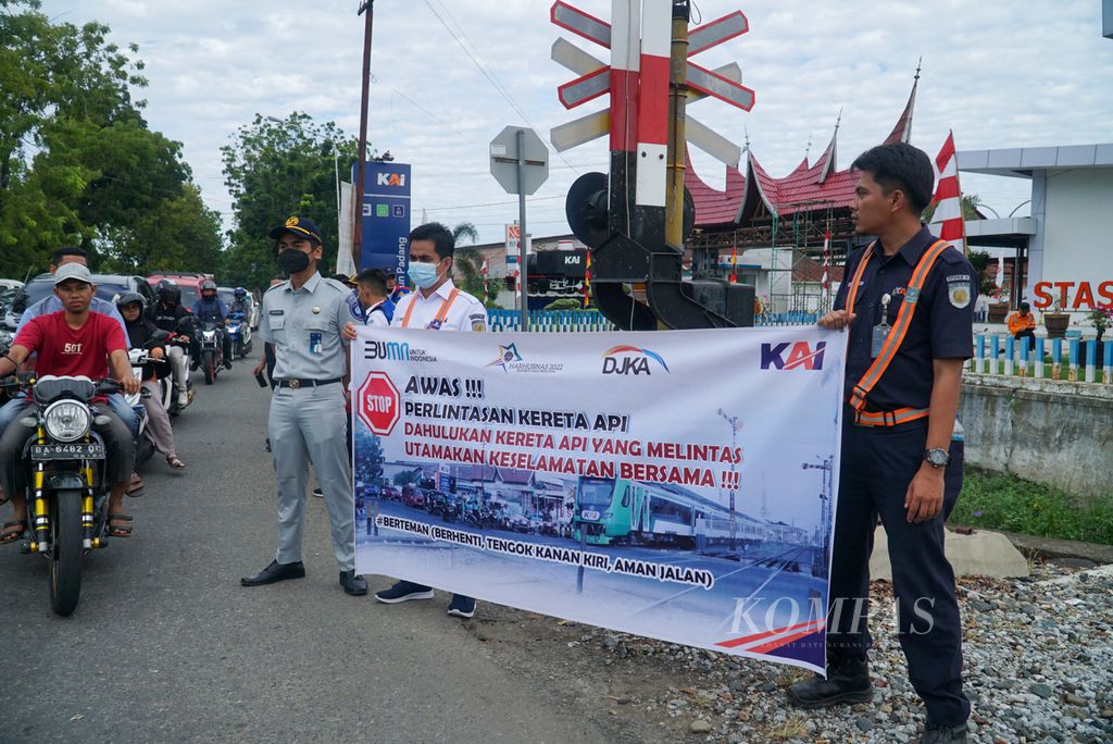 Petugas membentangkan spanduk imbauan kepada warga dalam kampanye keselamatan dalam rangka Hari Perhubungan Nasional di pelintasan sebidang depan Stasiun Padang, Kecamatan Padang Timur, Kota Padang, Sumatera Barat, Sabtu (27/8/2022). 