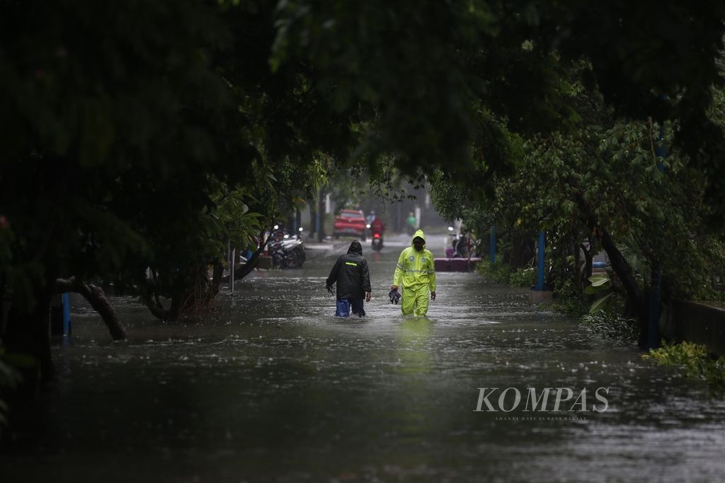 Residents passing through East Cempaka Putih Road in Central Jakarta, which was cut off due to high flooding, on Thursday (29/2/2024).