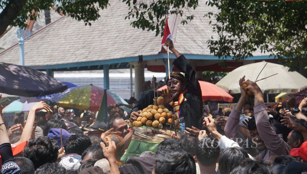 Seorang abdi dalem mempertahankan bendera Merah Putih sewaktu para warga berebut gunungan dalam rangka Grebeg Maulud di Masjid Agung Keraton Surakarta, Kota Surakarta, Jawa Tengah, Senin (16/9/2024). 