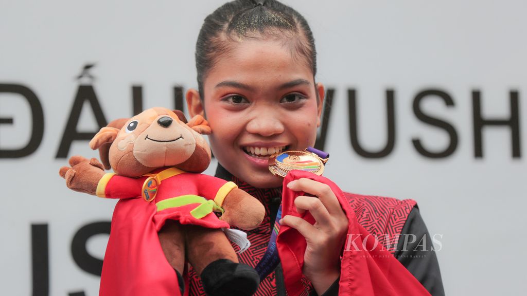Atlet wushu Indonesia, Alisya Mellynar, berpose bersama medali emas yang diraihnya dalam cabang wushu SEA Games Vietnam 2021 di Cau Giay Gymnasium, Hanoi, Vietnam, Sabtu (14/5/2022). Alisya merupakan atlet debutan di SEA Games.