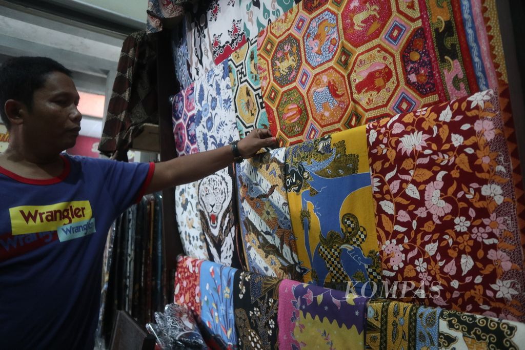 Gunisa (51) menata dagangannya di Pasar Batik Trusmi di Kabupaten Cirebon, Jawa Barat, Selasa (26/4/2022). Pedagang di pasar tersebut menanti berkah dari arus mudik Lebaran. Pemilik Batik Nefa ini menyiapkan aneka motif batik tulis seharga Rp 250.000 hingga lebih dari Rp 1 juta.