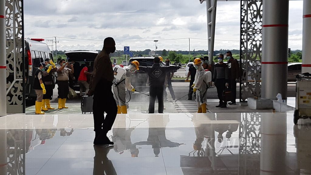 Pihak kepolisian menyemprotkan disinfektan kepada beberapa penumpang dari Jakarta di Bandara Tjilik Riwut, Palangkaraya, Kalteng, Selasa (31/3/2020).