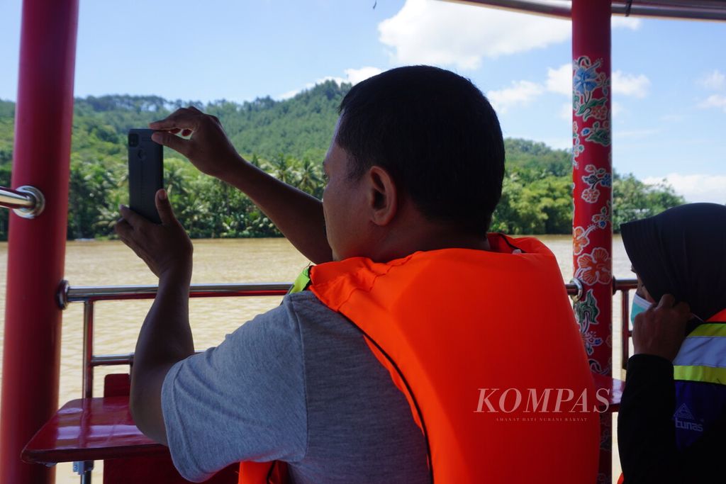 Penumpang mengambil foto saat mengikuti aktivitas wisata susur Sungai Serayu di Kecamatan Rawalo, Kabupaten Banyumas, Jawa Tengah, Minggu (19/2/2023). Selama masa uji coba, wisata ini bisa dinikmati warga secara gratis. 