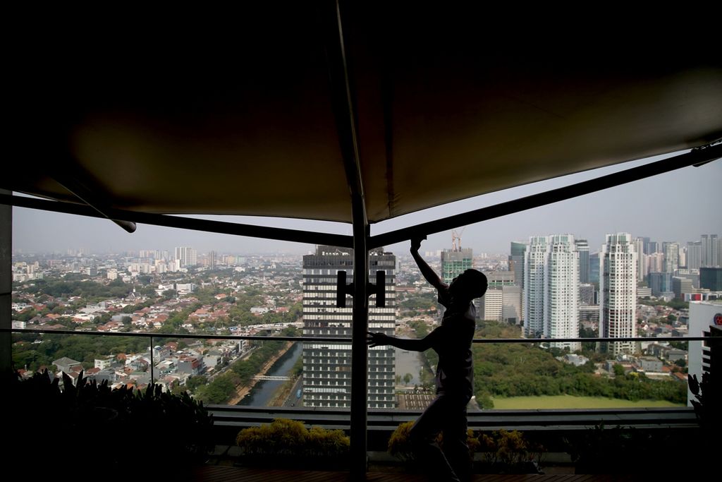 Petugas kebersihan bekerja dengan latar belakang kompleks perkantoran dengan ruang terbuka hijau di kawasan Sudirman, Jakarta, Kamis (19/9/2019). Berdasarkan Peraturan Daerah DKI Jakarta Nomor 1 Tahun 2012 tentang Rencana Tata Ruang Wilayah 2030, Jakarta menargetkan total luas ruang terbuka hijau mencapai 30 persen dari luas wilayah DKI pada tahun 2030.  