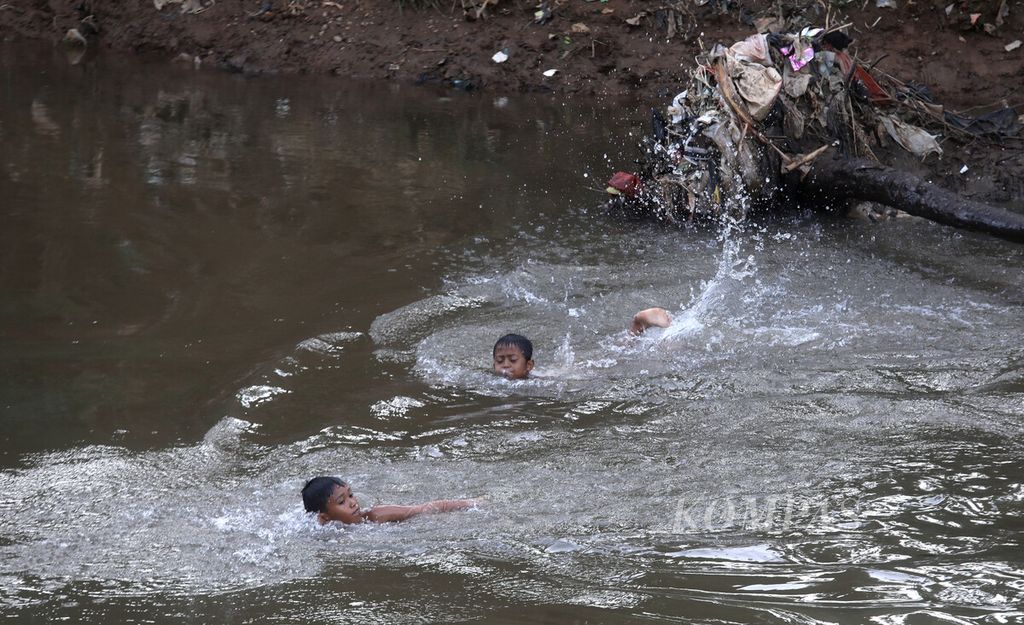 Anak-anak berenang di Kali Cilwiung di kawasan Balekambang, Condet, Jakarta Timur, Senin (23/1/2023). 