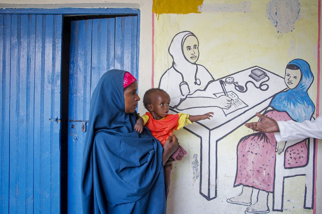 Seorang ibu warga Somalia tengah menggendong anaknya yang menderita malnutrisi karena dampak kekeringan, di depan sebuah pusat layanan kesehatan yang dikelola lembaga Action against Hunger, di Mogadishu, Somalia pada Minggu (5/6/2022).