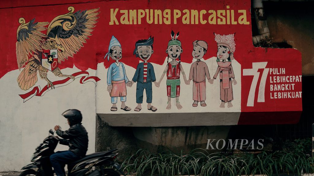 Warga melintasi mural bergambar anak-anak yang mengenakan pakaian adat Nusantara dan bergandengan tangan di Tebet Timur, Tebet, Jakarta Selatan, Rabu (14/9/2022). Mural yang menyerukan toleransi dan keberagaman terus disuarakan warga di ruang publik untuk lekas bangkit dan menjadi lebih kuat. 