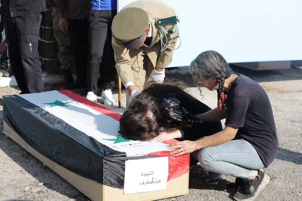 Keluarga korban meratap di samping peti jenazah korban di luar rumah sakit di Homs, Suriah, Jumat (6/10/2023), dalam pemakaman korban serangan pesawat nirawak di sebuah akademi militer, sehari sebelumnya.
