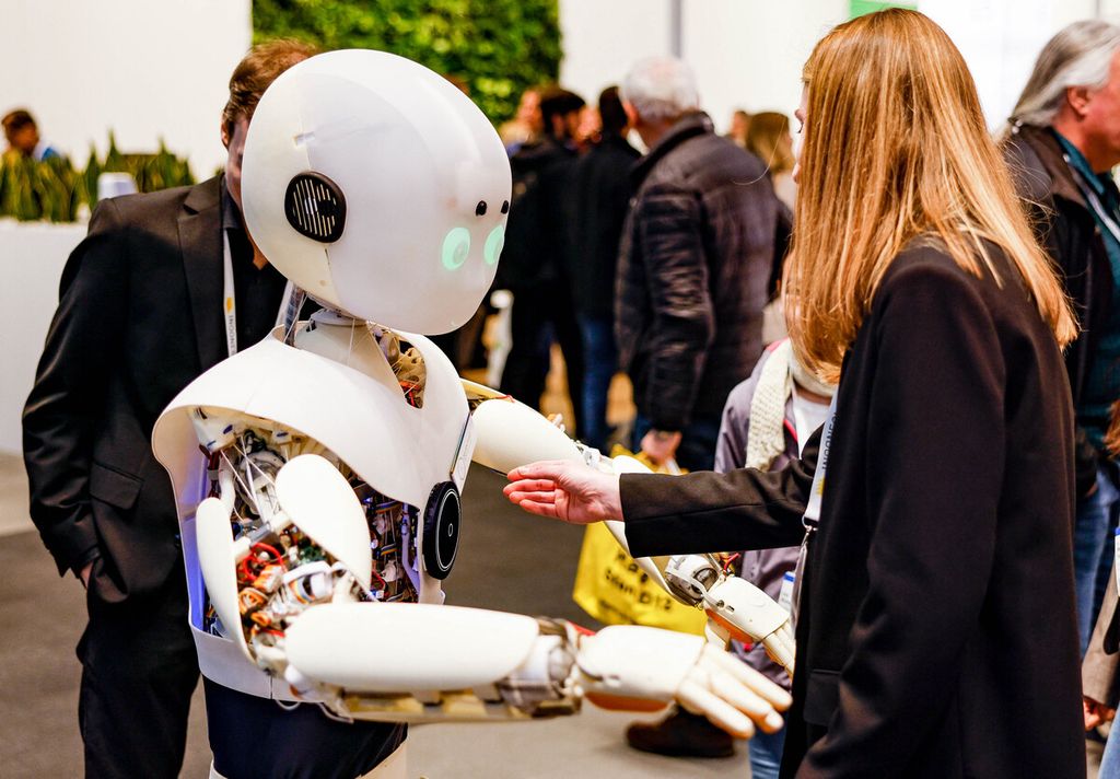Dalam <i>file</i> foto yang diambil 17 April 2023 ini, seorang perempuan berinteraksi dengan robot karya Devanthro - The Robody Company di depan boks foto di Hannover Messes 2023, pameran teknologi Hanover, di Hanover, Jerman. 