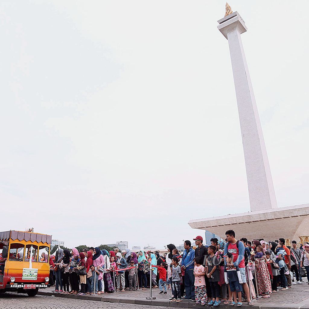 Warga antre untuk naik ke kereta wisata seusai berkunjung ke  Monumen Nasional, Jakarta,  pada hari terakhir cuti bersama Natal, Selasa (26/12). Ribuan warga Jakarta dan sekitarnya memanfaatkan hari libur  dengan mengunjungi tempat-tempat wisata yang ada di Ibu Kota.