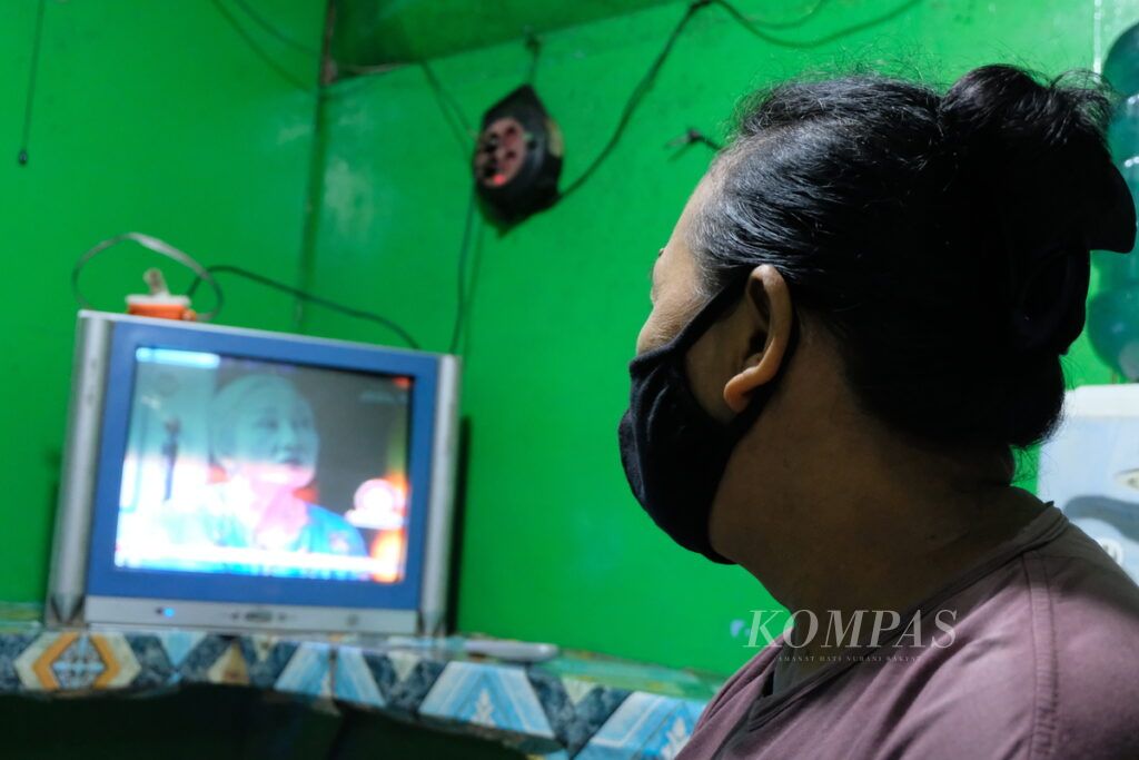 Seorang pedagang makanan menonton sinetron yang disiarkan di televisi, Senin (15/3/2021) di Jakarta. Sinetron jadi salah satu hiburan warga yang mudah diakses dan gratis.