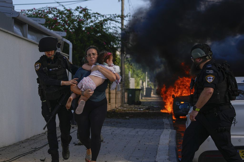 Polisi mengevakuasi seorang perempuan dan anak kecil di Ashkelon, Israel selatan, dari lokasi yang dihantam roket dari Jalur Gaza, Sabtu (7/10/2023). 