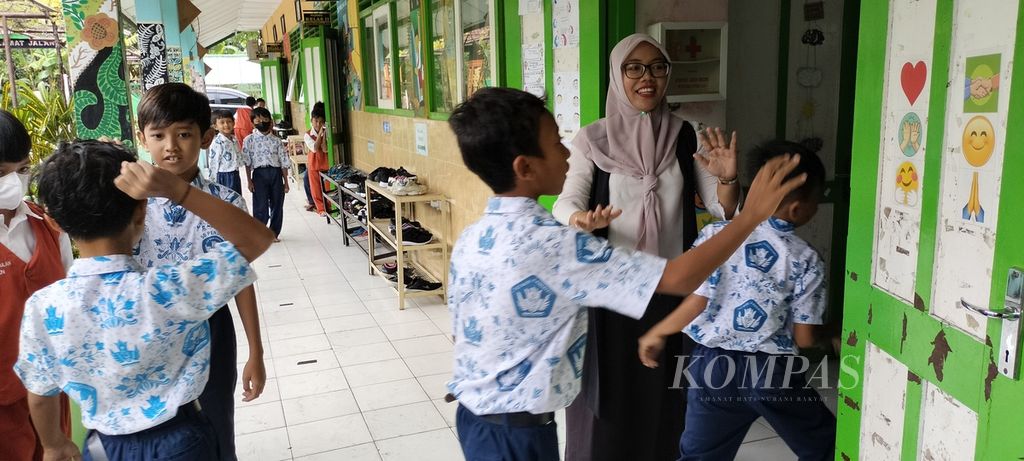 Students at Pendulan Public Elementary School, Sleman Regency, Special Region of Yogyakarta, (15/2/2023), are excited to enter the classroom. One of the teachers welcomes students with a greeting style that is freely chosen by students so that they feel happy and happy while studying at school.