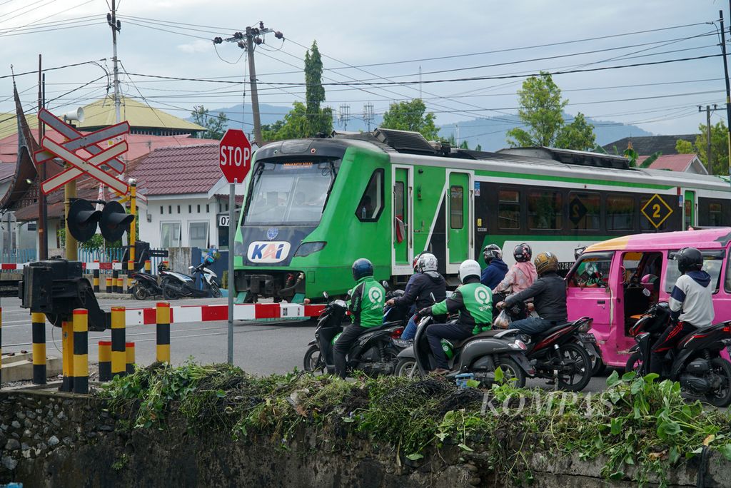 Pengendara berhenti di perlintasan sebidang saat kereta api Minangkabau Ekspres melintas di depan Stasiun Padang, Kecamatan Padang Timur, Kota Padang, Sumatera Barat, Sabtu (27/8/2022). 