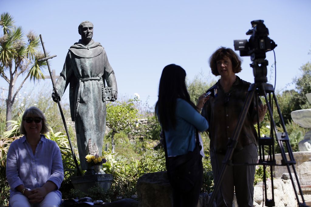 Reporter mewawancara warga di dekat patung Junipero Serra di Carmel Mission, Carmel-By-The-Sea, California, Amerika Serikat, 23 September 2015.  