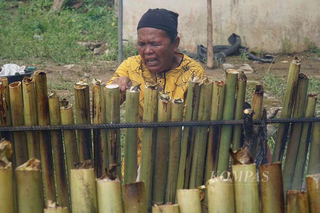 Warga memperbaiki posisi tabung lamang (lemang) agar matang merata dalam acara "Malamang Sakampuang" di Kelurahan Aie Pacah, Kecamatan Koto Tangah, Kota Padang, Sumatera Barat, Sabtu (31/12/2022). 
