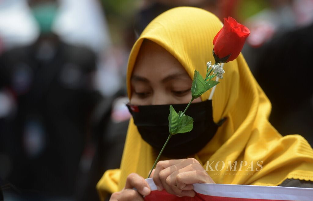 Salah satu pekerja perempuan membawa bunga sebagai simbol aksi damai dalam menolak RUU Cipta Kerja di depan Kantor DPRD Jawa Tengah, Kota Semarang, Jumat (16/12/2020). Buruh dari berbagai serikat pekerja tersebut berkomitmen menjalankan aksi dengan damai.
