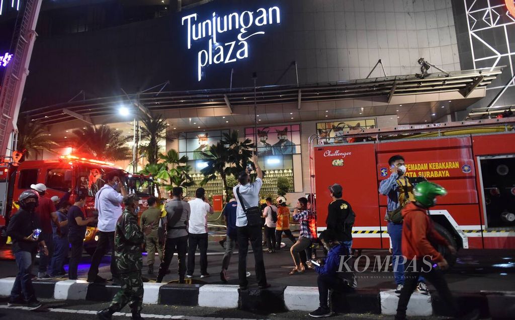 Kesibukan petugas dan jurnalis di Tunjungan Plaza, Kota Surabaya, yang mengalami kebakaran, Rabu (13/4/2022). Api pertama kali terlihat di Tunjungan Plaza 5 pada pukul 17.40 WIB. Sebanyak 20 truk pemadam kebakaran, termasuk di dalamnya tiga <i>sky lift</i>, dikerahkan untuk memadamkan api. Kejadian yang membuat Jalan Embong Malang ditutup itu tidak menimbulkan korban jiwa.