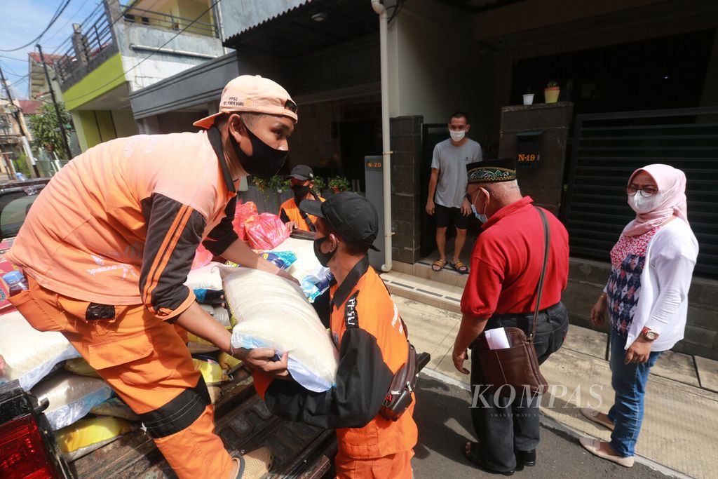 Petugas PPSU menurunkan paket sembako bantuan untuk warga yang isolasi mandiri (isoman) di rumah karena salah satu atau lebih anggota keluarganya positif Covid-19 di RW 010 Kelurahan Pondok Bambu, Jakarta Timur, Sabtu (26/2/2022).