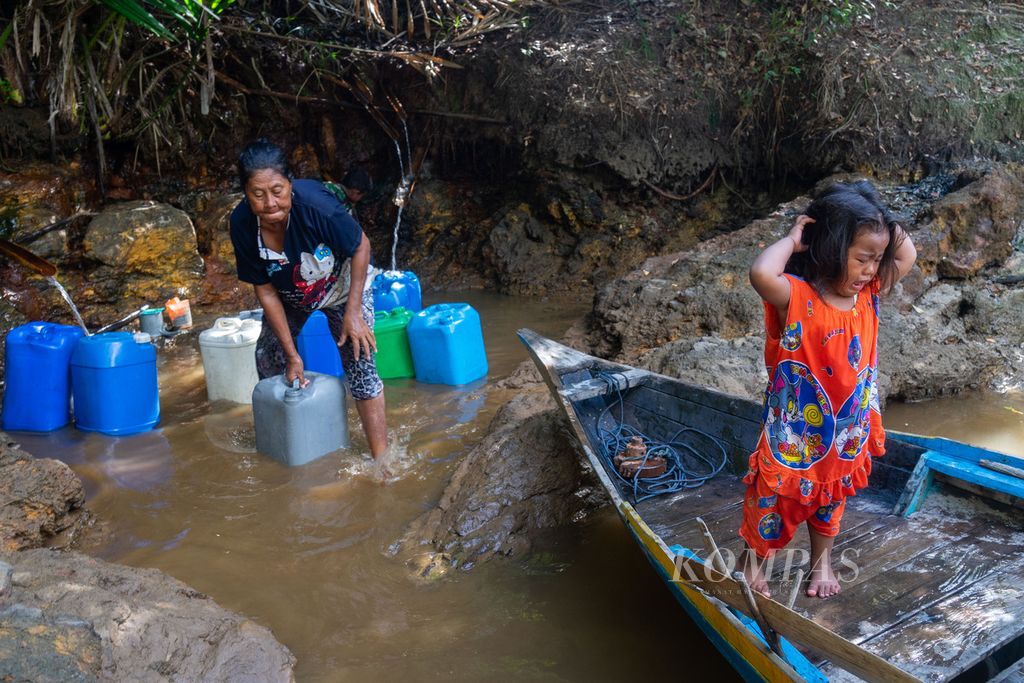 Seorang warga Suku Laut, Rusna, mengambil air bersama cucunya yang berusia 2,5 tahun di Sungai Pinang, Kecamatan Temiang Pesisir, Kabupaten Lingga, Kepulauan Riau, Minggu (17/7/2022). 
