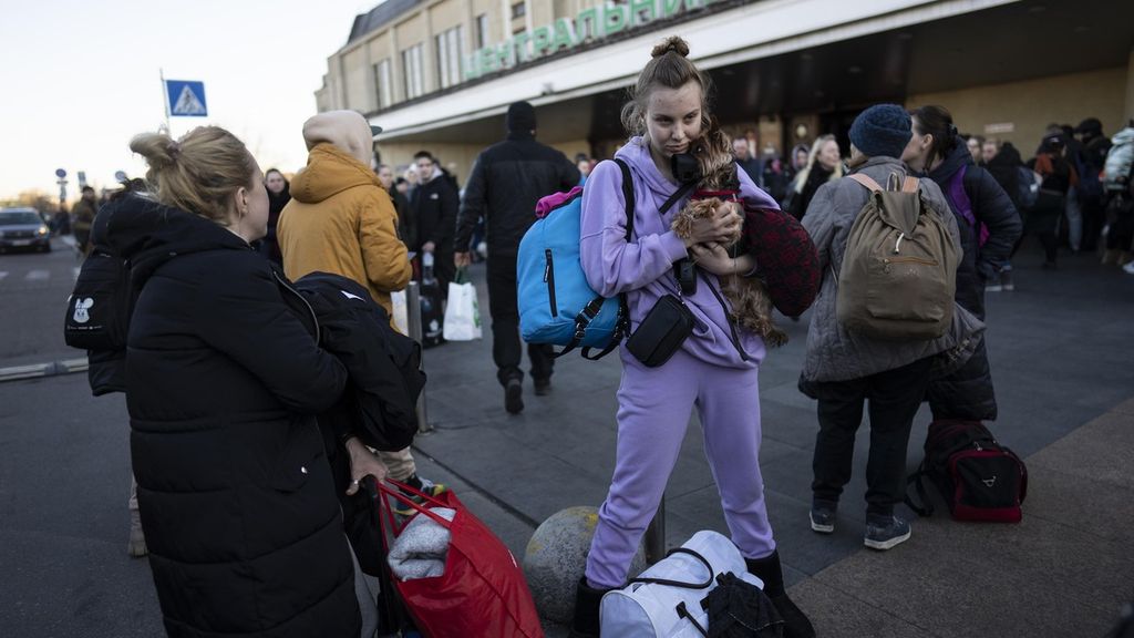 Daryna Kovalenko menggendong anjingnya saat tiba di stasiun kereta Kiev setelah meninggalkan rumahnya di Chernihiv, Ukraina, melalui koridor kemanusiaan, Senin (21/3/2022) waktu setempat. Perang telah membuat hingga 12 juta orang terpaksa mengungsi di dalam dan luar Ukraina. 