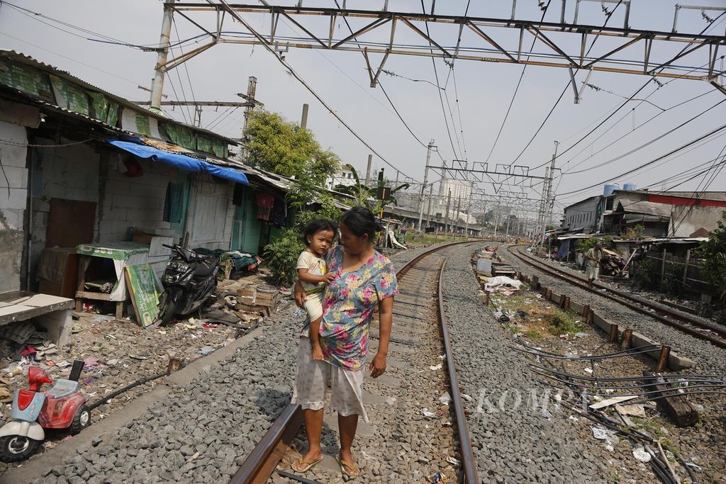 Residents seek fresh air in an open space located between the train tracks that divide densely populated semi-permanent residences in the Pademangan area of North Jakarta on Thursday (17/7/2023).
