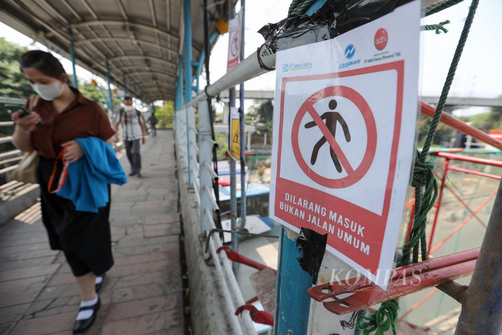 Warga melintas di samping revitalisasi halte Transjakarta Cawang UKI, Jakarta, Kamis (12/9/2023).