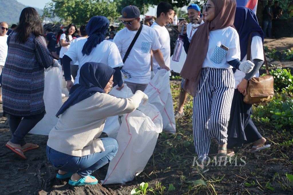 Para peserta kegiatan bersih-bersih pantai memungut sampah di Pantai Karangria, Manado, Sulawesi Utara, Kamis (31/10/2019).