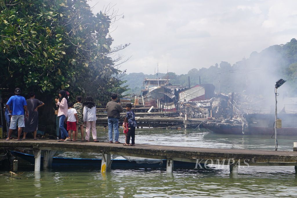 Warga melihat kapal yang masih terbakar di sekitar Dermaga Wijayapura, Cilacap, Jawa Tengah, Rabu (4/5/2022) pagi. 